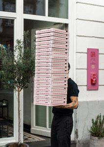 Person trägt einen hohen Stapel Pizzakartons von Gotti